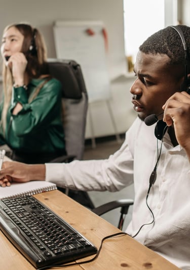 Un homme et une femme assis à un bureau en train d'appeler une autre personne par téléphone