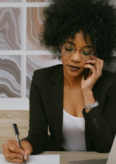 Une femme en tailleur noir et lunettes qui parle au téléphone portable