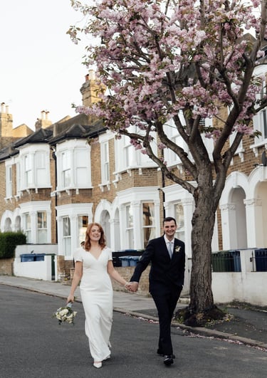 bride and groom holding hands and walking down the street during the sunset
