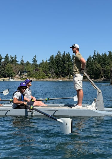 Team rowing on the water with a coach guiding them during a leadership and team-building event