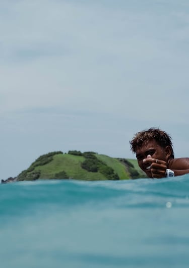 A smiling surfer giving a heart up in turquoise ocean water in Tanjung Aan