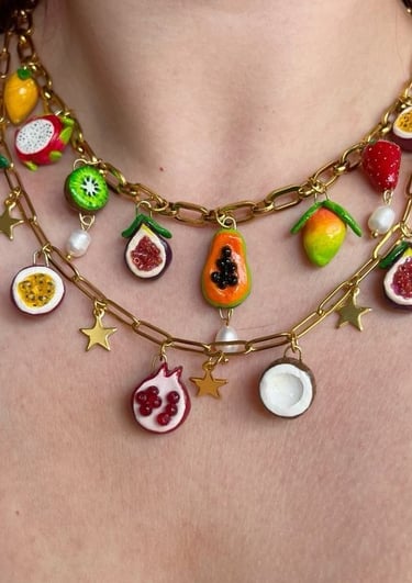 Dos collares colocados en el cuello, con charms en forma de frutas
