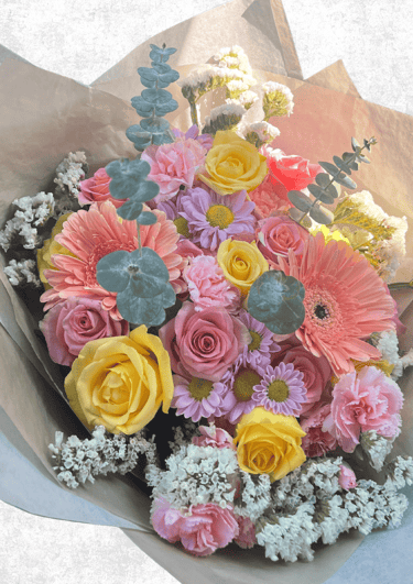 Ramo de rosas, gerberas, margaritas, claveles y follaje en tonos rosa, morado y amarillo