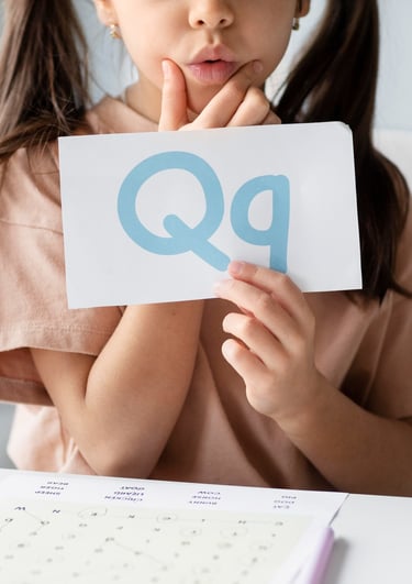 Een jong meisje dat een papieren bord vasthoudt met de tekst "qq"