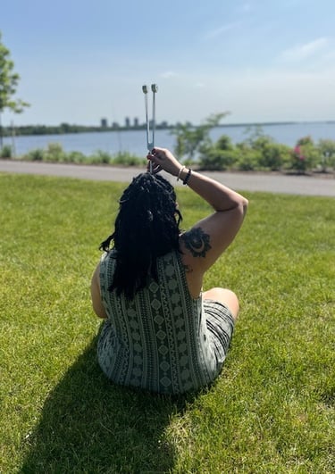 a woman sitting on the grass with a stick in her hand