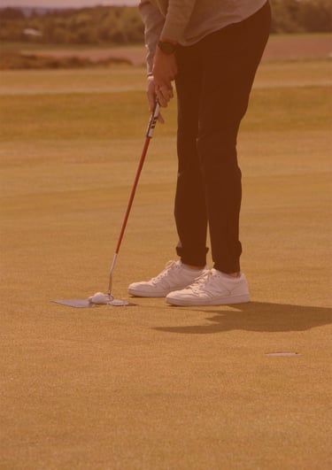 A golfer setting up for a putt on the green, focusing on their stroke, with a serene golf course setting in Aberdeen