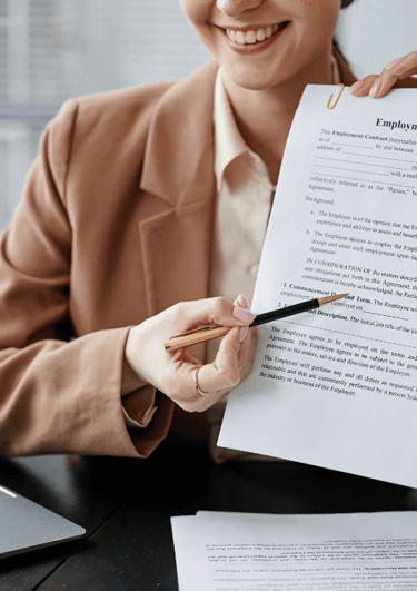 a woman in a suit is holding a pen and an employment contract