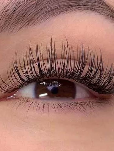 a woman with classic eyelash extensions and looks long eyelashes and lashes on her eyes