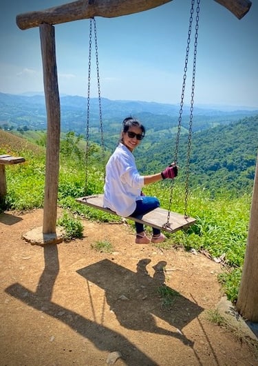 Parichad Khongon on a swing in the mountains overlooking the Thai landscape by Peter Pickering