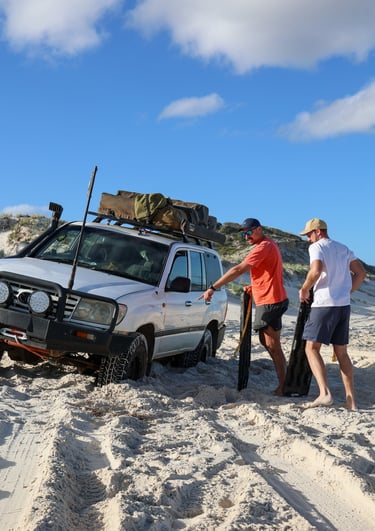 4x4 voertuig wordt uitgegraven met recovery boards in het zand van West Australië