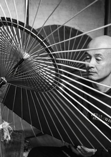 A Japanese artisan meticulously crafts a traditional wagasa oil-paper umbrella with bamboo ribs.