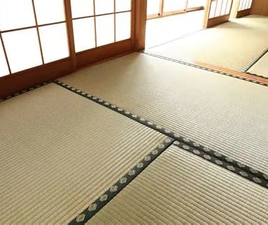 Traditional Japanese washitsu room featuring woven tatami mat flooring and sliding shoji screen doors.