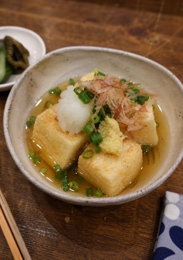 Agedashi Do-fu, a Japanese dish of deep-fried tofu in dashi broth with green onions and bonito flakes.