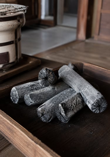 Traditional binchotan white charcoal sticks on a wooden tray for Japanese konro grill cooking.