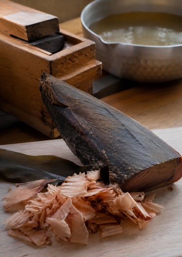 Katsuobushi block with bonito flakes and kombu seaweed on a wooden board for making Japanese dashi broth.