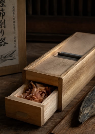 Traditional Japanese katsuobushi shaver with wooden box and dried bonito flakes.