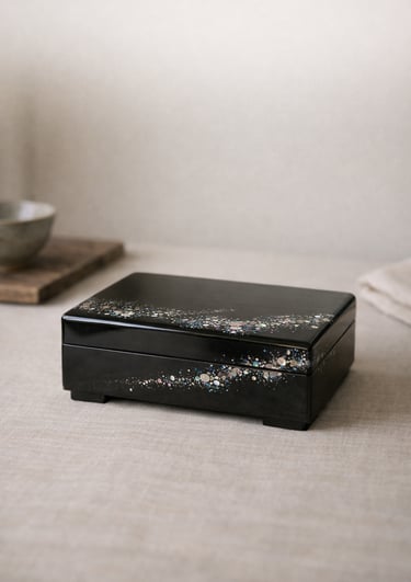 Elegant black lacquer jewelry box with iridescent mother of pearl inlay on a linen surface.