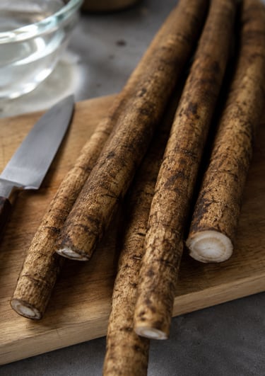 Fresh raw burdock root on a wooden cutting board with a paring knife for healthy cooking.