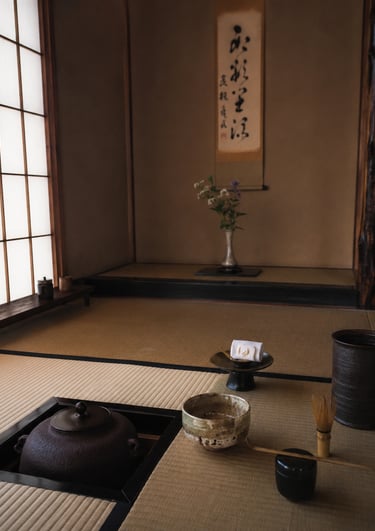 Traditional Japanese tea room featuring a matcha bowl, whisk, and cast iron kettle on tatami mats.