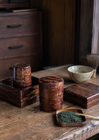 Traditional Japanese cherry bark tea canisters and matcha green tea set on a rustic wooden table.