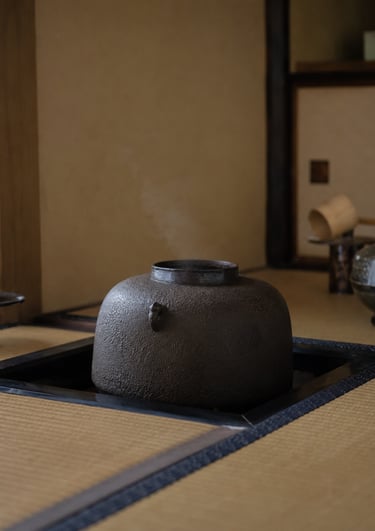 Steaming traditional Japanese cast iron tea kettle sitting in a sunken hearth on a tatami mat.