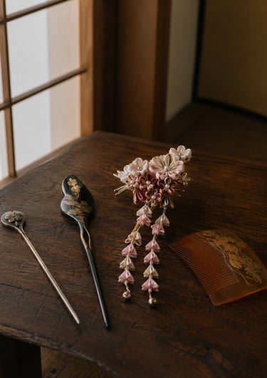 Traditional Japanese tsumami zaiku kanzashi hairpins and a decorative comb on a rustic wooden table.