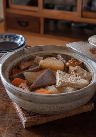 Traditional Japanese oden stew with daikon radish, konjac, and tofu served in a ceramic donabe pot.