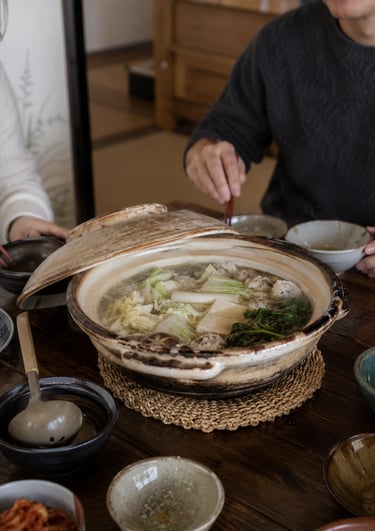 A ceramic donabe pot filled with Japanese nabemono hot pot containing tofu, napa cabbage, and meatballs.