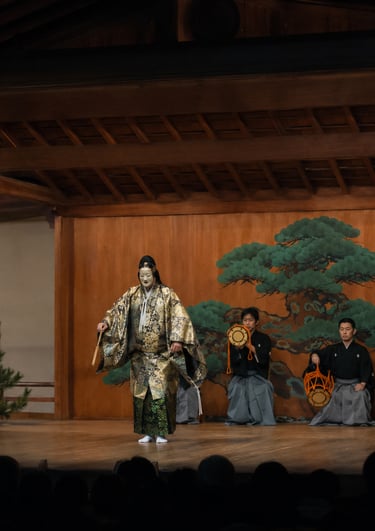A Japanese Noh theatre performance featuring a masked actor in a gold kimono and musicians on a wooden stage.
