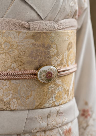 Close-up of a traditional Japanese silk kimono with a floral gold obi belt and decorative obidome accessory.