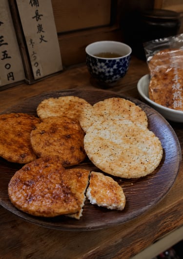 Traditional Japanese senbei rice crackers on a wooden plate with green tea.