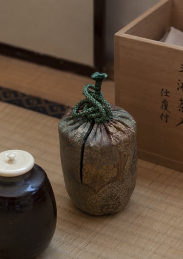 Traditional Japanese tea ceremony tea caddy in a silk brocade shifuku bag on a tatami mat.