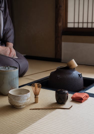 Traditional Japanese tea ceremony set on a tatami mat with matcha whisk, bowl, and iron kettle.