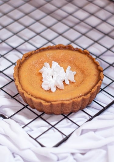 tartaleta mini de pay de queso con crema batida enfriándose sobre una rejilla negra de alambre.