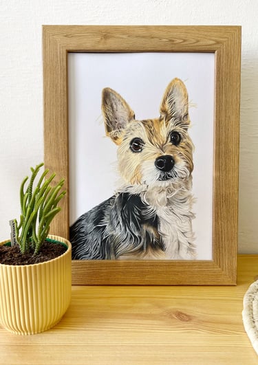 Custom framed terrier pet portrait painting on a wooden shelf next to a small potted cactus.