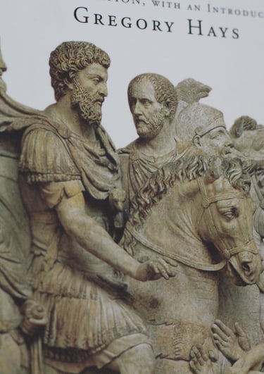 Close-up of the Meditations book cover by Marcus Aurelius featuring Roman relief sculptures of soldiers and horses.