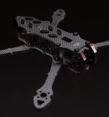 A lightweight carbon fiber FPV racing drone frame with a matte finish on a dark background.