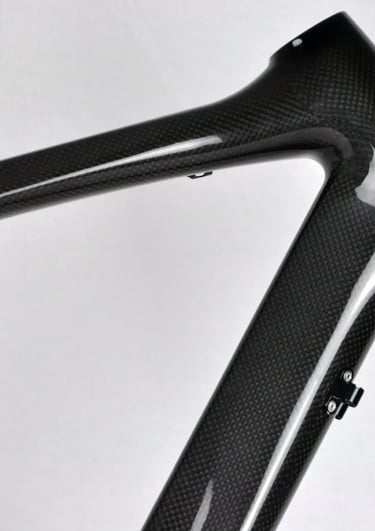 Close-up of a lightweight carbon fiber bicycle frame showing the woven texture and head tube.