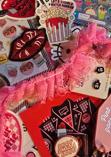 piles of earrings, stickers, patches, postcards and snippets of hot pink lace