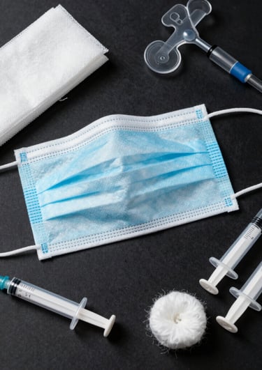 A clean, modern display of various medical supplies including gloves, masks, and syringes arranged neatly on a white background.