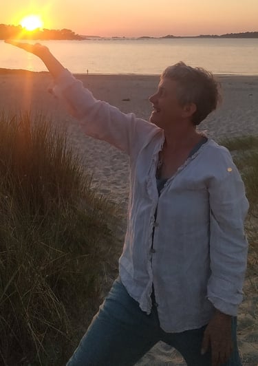 a woman is standing on a beach with her arms outstretched out to the sun