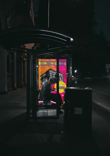 Campaign poster displayed in illuminated bus shelter at night showing grand reopening design