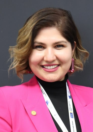 Professional woman in pink coat and black blouse smiling