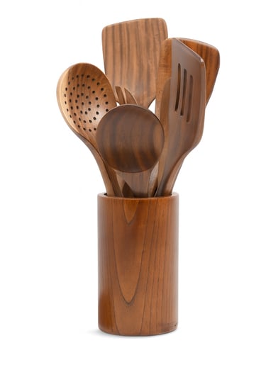 Teak wood kitchen utensils arranged in a matching round holder, including spatulas and spoons