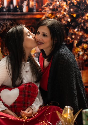 a girl kissing her mother under the Christmas tree