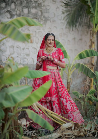 “Traditional Indian bride in red bridal choli posing in a garden – bridal photography in Vadodara, G