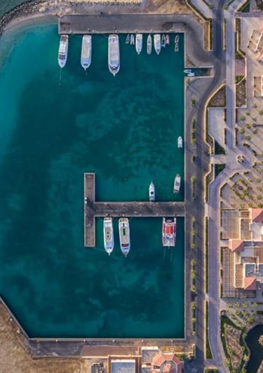 Aerial view of a luxury coastal resort marina with yachts anchored in turquoise water.