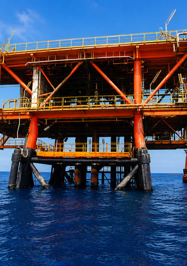An offshore oil rig platform and drilling equipment standing in the deep blue ocean water.