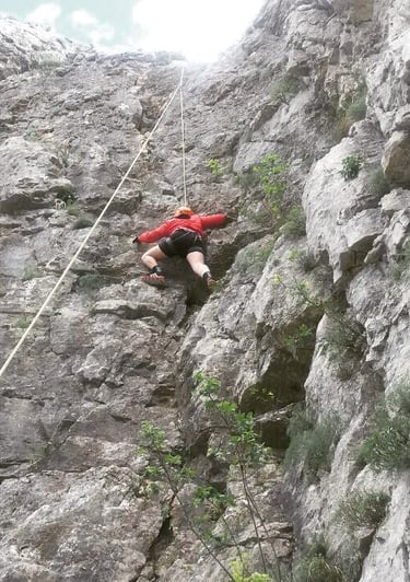 a man in a red shirt is climbing a steeple