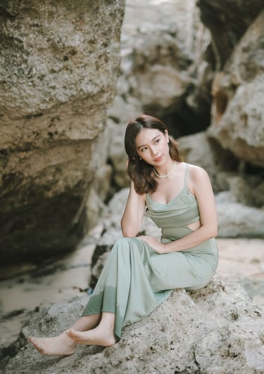 Portrait of woman sitting near rock formation during photoshoot at Geger Beach Nusa Dua Bali